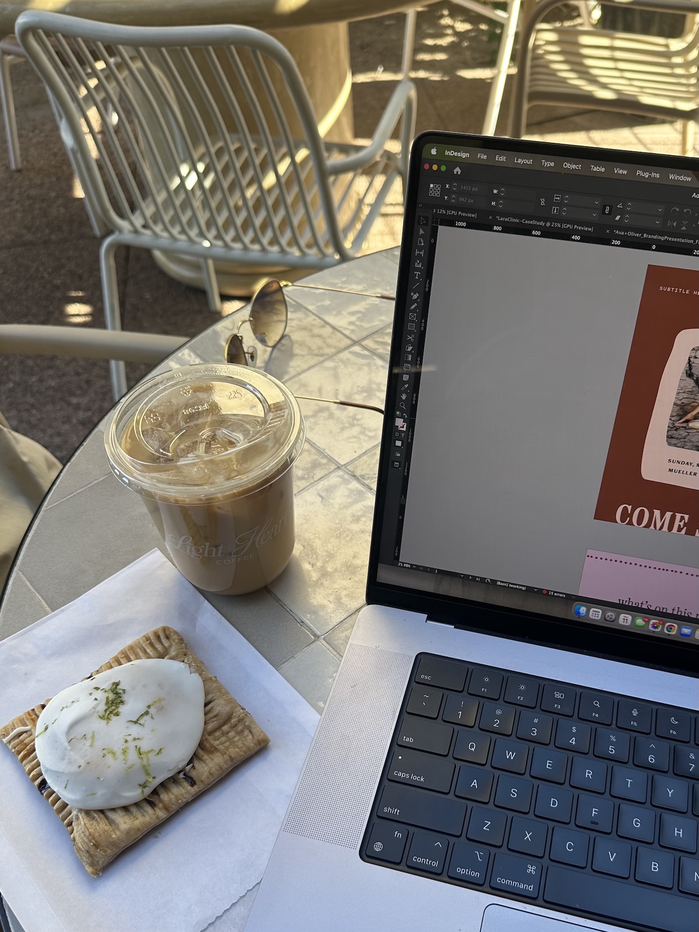 Designing a client branding project on a laptop while building an email list with Pinterest strategy, iced coffee at an outdoor café table