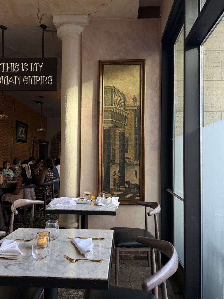Warm, softly lit restaurant interior with marble tables, folded linen napkins, gold flatware, and vintage artwork, reflecting a slow burn content strategy and how to make content last longer with thoughtful visual storytelling.