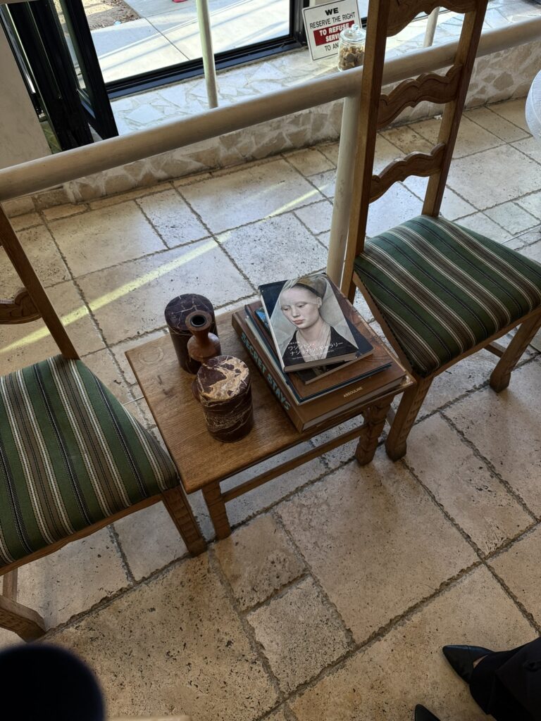 Cozy seating area with green striped vintage chairs, a rustic wooden table, stacked art books, and decorative objects, illustrating a content repurposing strategy and how to reuse old content to support long term content marketing.